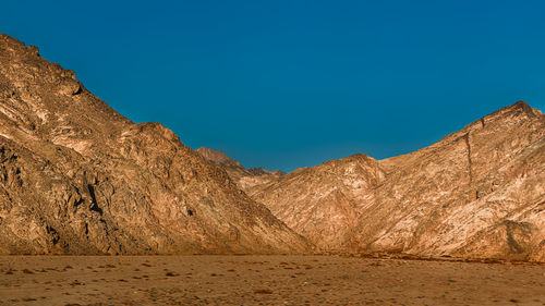 Scenic view of desert against clear blue sky