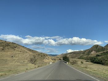 Road leading towards mountains against sky