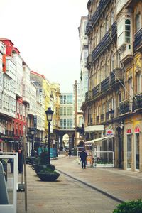 People walking on footpath by buildings against sky