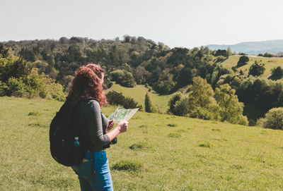 Woman looking at map while standing on field