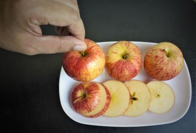 High angle view of person holding apple on table