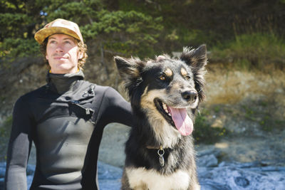 Man looking away while relaxing with dog at beach