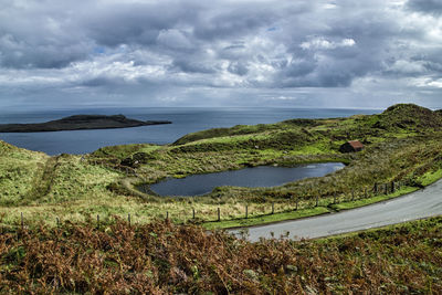 High angle view of countryside against sea and cloudy sky