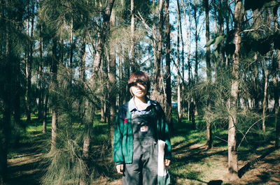 Portrait of smiling young woman standing in forest