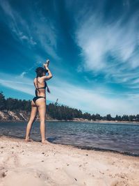 Woman standing at beach against sky
