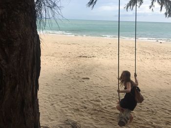 Woman standing on tree trunk at beach