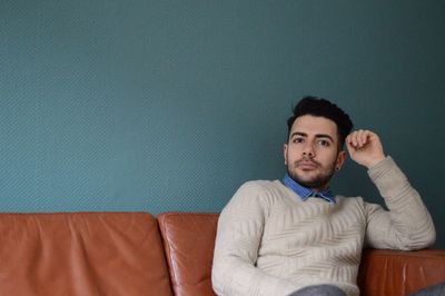 Portrait of a smiling young man sitting on sofa