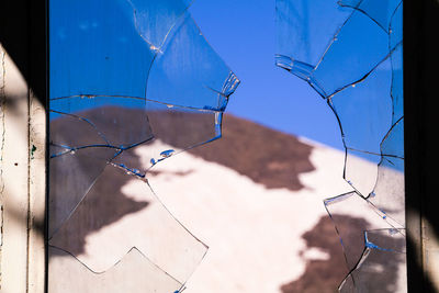 Close-up of broken glass window against building