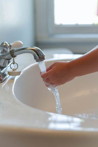 Close-up of girl washing hands in bathroom at home