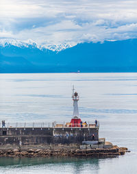 View of lighthouse on sea against cloudy sky