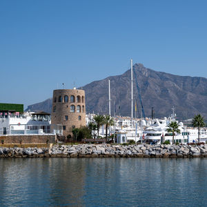 Buildings by sea against clear sky