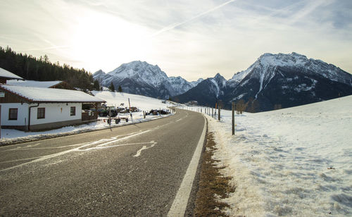 Road by snowcapped mountains against sky