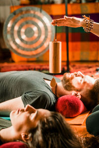 Therapist holding equipment over couple while performing music therapy at spa