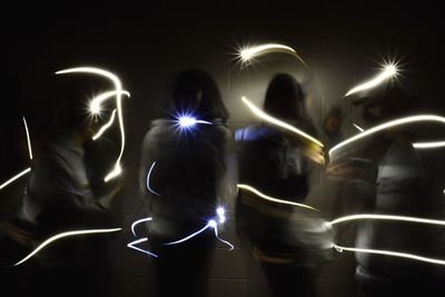 People standing by light trails at night