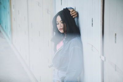 Young woman standing against wall