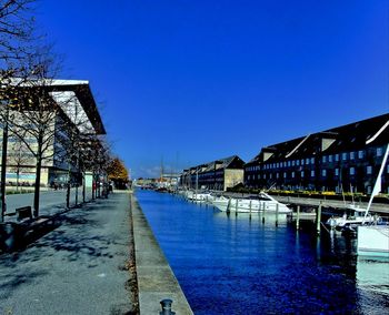 View of canal in city against clear blue sky