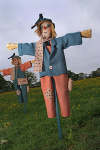 Scarecrow on grassy field against sky