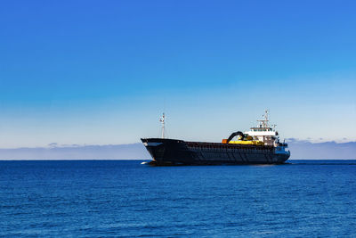 Ship sailing on sea against blue sky