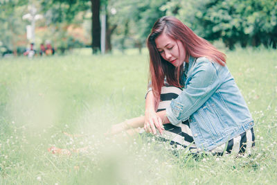 Side view of young woman lying on field