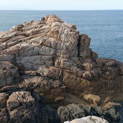 Rock formation by sea against clear sky