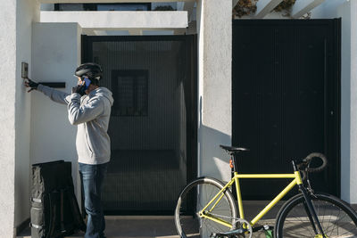 Delivery man talking on phone and ringing doorbell