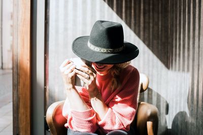 Woman sat hiding behind a hat drinking coffee in a cafe in fall