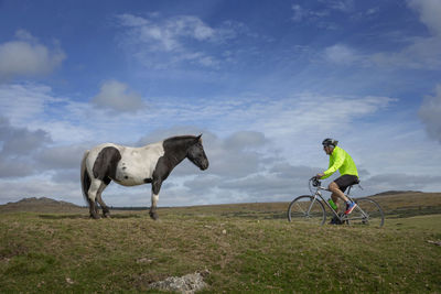 Horse riding bicycle on field