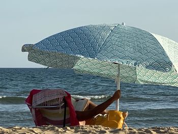 Deck chairs on beach against clear sky