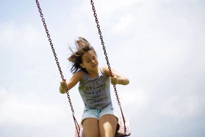 Low angle view of girl playing on swing