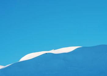 Low angle view of snow mountain against clear blue sky