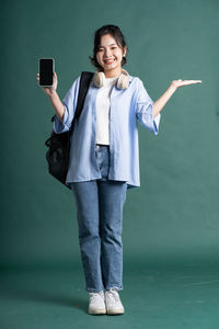 Portrait of young woman standing against wall