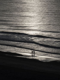 Silhouette people standing on beach by sea