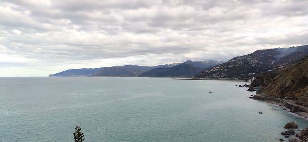 Scenic view of sea and mountains against sky