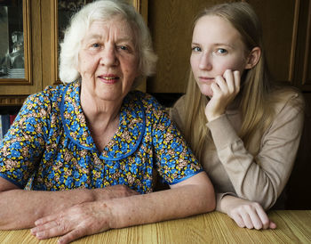 Portrait of granddaughter and grandmother sitting at home