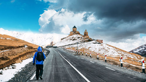 Rear view of people walking on road against sky