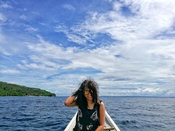 Portrait of woman standing by sea against sky