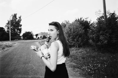 Portrait of woman eating ice cream while walking on road