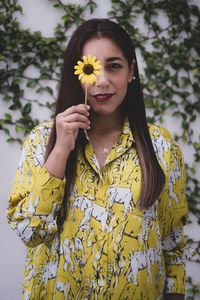 Portrait of young woman holding yellow flower