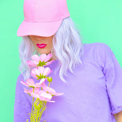 Woman holding pink flower against blue background