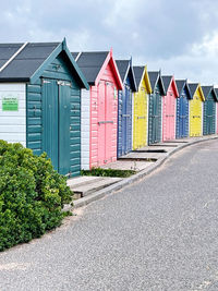 Beach huts by buildings against sky in city