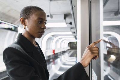 Young woman touching digital display at subway station