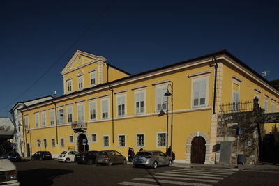 Cars on road by buildings against clear sky in city