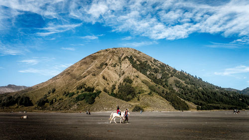 People riding horses on mountain against sky