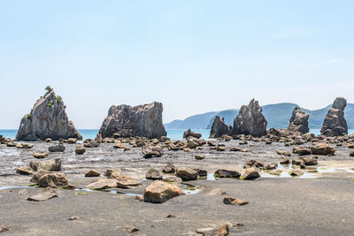 Rocks by sea against clear sky