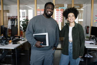 Portrait of happy male and female colleagues standing together at office