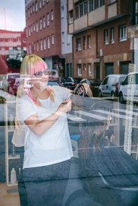 Female hairdresser styling customer hair in salon seen through window