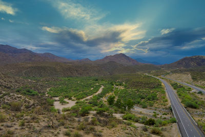 Scenic view of road amidst field against sky