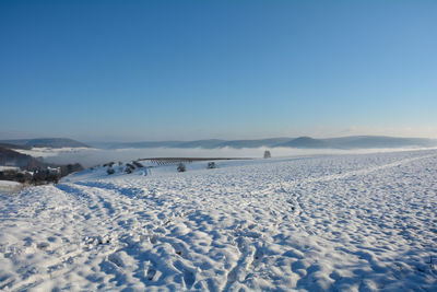 Snow landscape with fields and fog in the valley and with blue sky in spessart, bavaria, germany