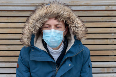 Man wearing mask and fur coat against wall