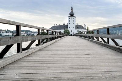 Bridge over canal by building against sky